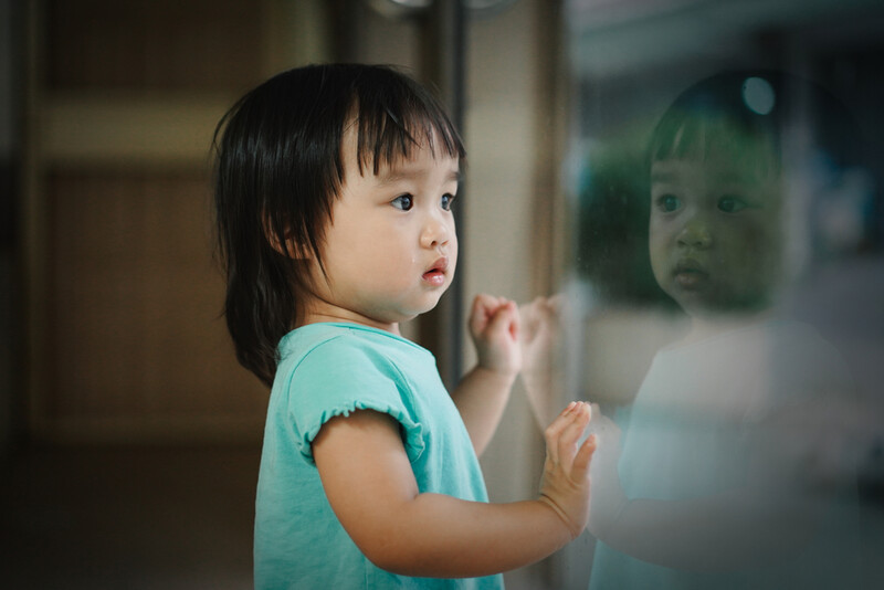 Asian toddler looking out window