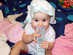 child mouthing a remote control